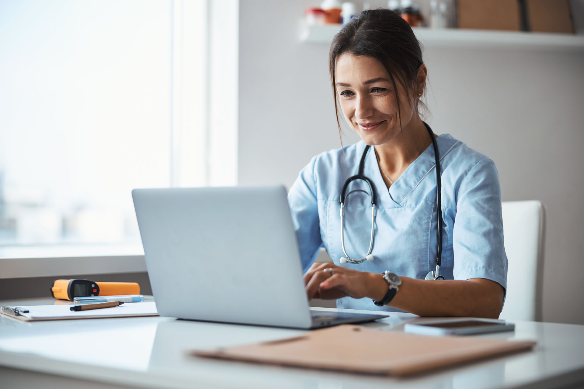 Joyful,Female,Doctor,Using,Notebook,In,Clinic Joyful female doctor using notebook in clinic