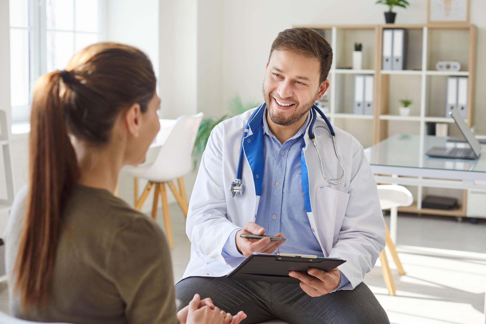 Woman patient talking with friendly young male doctor therapist
